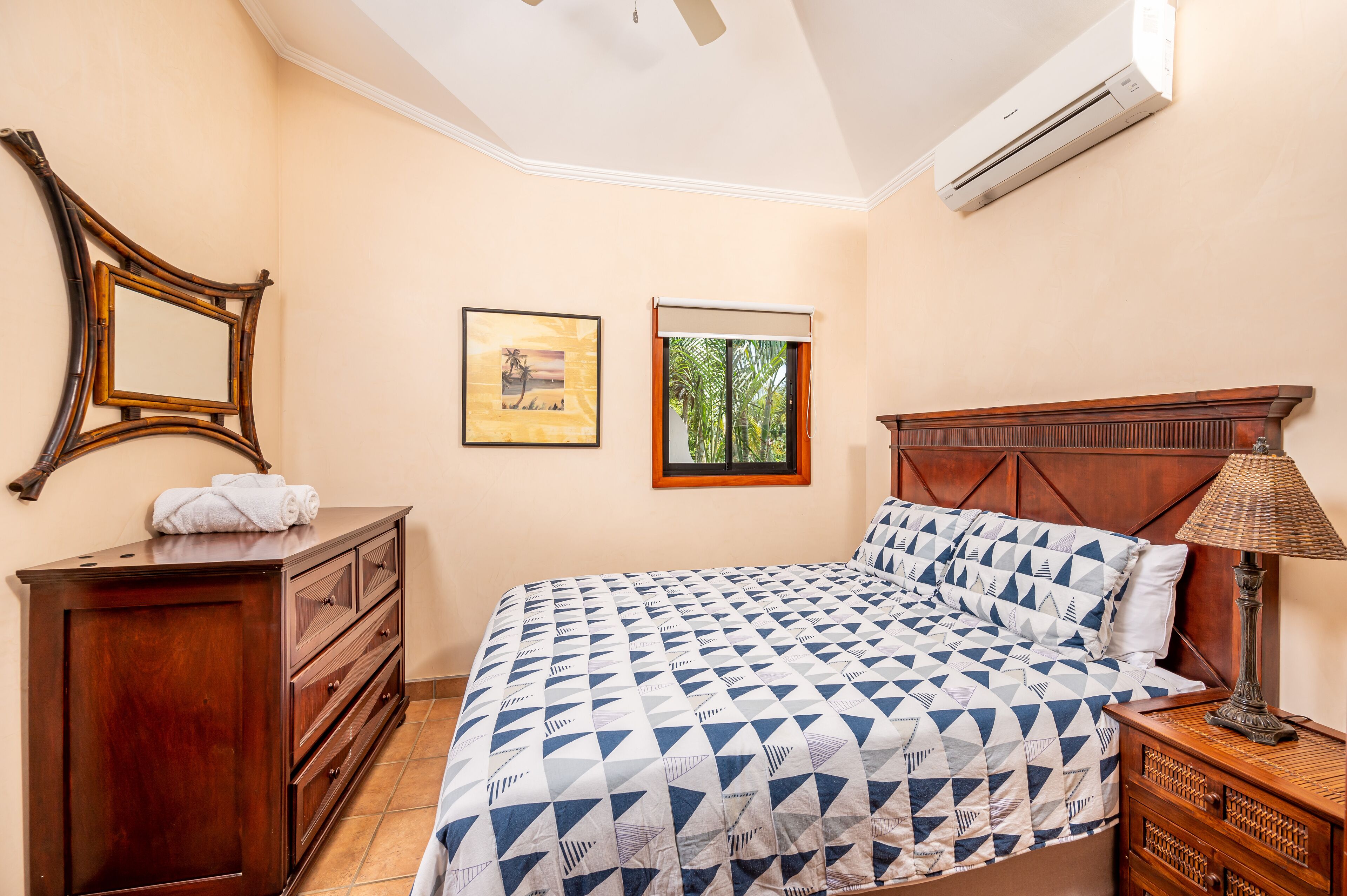 A bedroom with a bed, wooden dresser, and a nightstand.