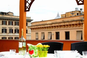 A table set for dining with a bottle of wine, a decorative fruit, and a bouquet of yellow flowers. - Vatican Penthouse with Terrace - St Peter's Dome view (Roma)