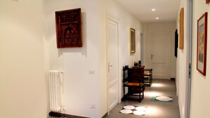 Un couloir avec un radiateur, une chaise en bois et une porte au fond.