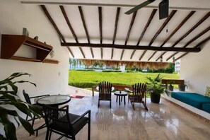 An outdoor patio with a thatched-roof structure, seating, and a view of a well-maintained lawn. - 1-Bedroom Unit With Convenient Access to the Pool and Beach (Cozumel)