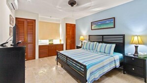 A bedroom with a bed, bedside lamps, a ceiling fan, and a painting on the wall. - 1-Bedroom Unit With Convenient Access to the Pool and Beach (Cozumel)