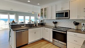 A modern kitchen with white cabinetry, a stainless steel oven, and a microwave. - The Salty Spot | Family Favorite Oceanfront Retreat w/Beach Access (Surf City)