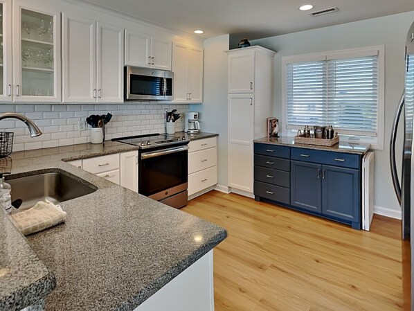A modern kitchen with white cabinets, a stainless steel sink, and a built-in microwave.