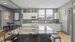 Una cocina con encimera de mármol, armarios blancos y lavavajillas integrado.