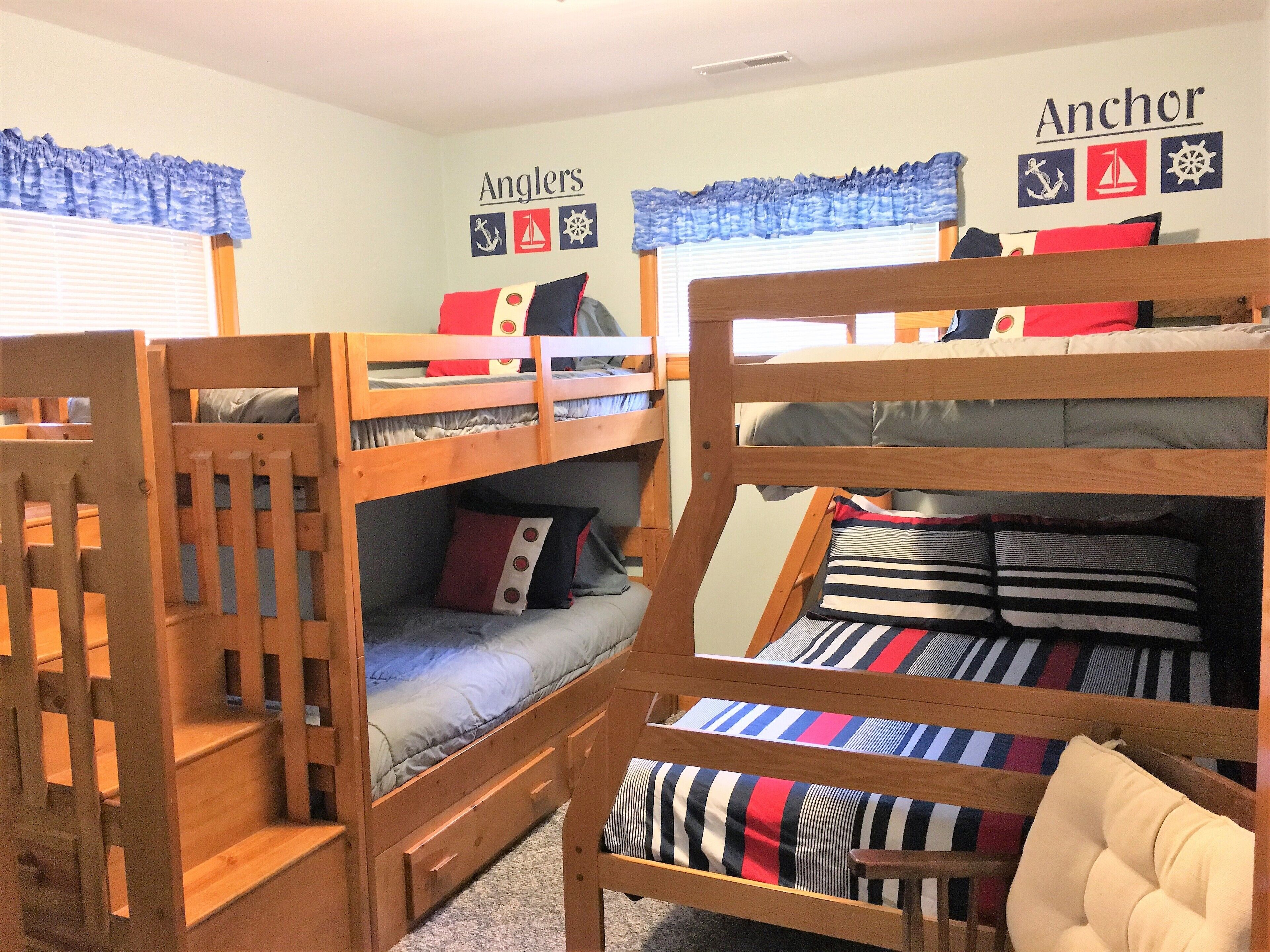 A bunk bed room with a window, a wall with nautical-themed decorations, and a wooden chair.