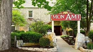 Un bâtiment en pierre avec une enseigne indiquant « MON AMI » et un chemin menant à l’entrée.