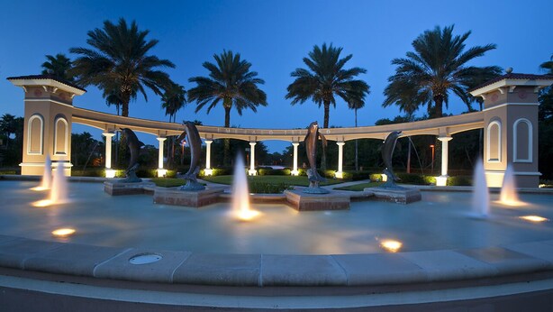 A fountain with multiple water jets, surrounded by palm trees and a pavilion with the word "EMERALD" on it.