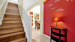 A wooden staircase leading to a room with a red wall and a small table with a lamp.