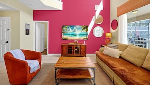 A living room with a vibrant pink wall, a wooden coffee table, a sofa, and a painting of a beach scene.