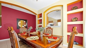 A dining room with a wooden table set for four, surrounded by ornate chairs.