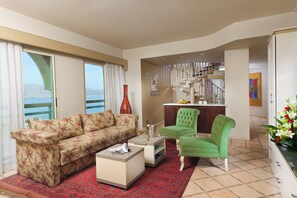 A living room with a sofa, a coffee table, and a chair. There is a view of the sea through large windows. - Herods Palace Hotels & Spa Eilat (Eilat)