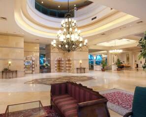 A spacious lobby with a grand chandelier, a reception desk, and a seating area with a patterned rug. - Herods Palace Hotels & Spa Eilat (Eilat)