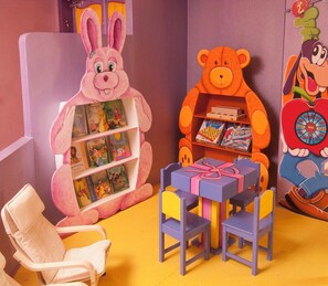 A children's play area with a large pink rabbit figure, an orange bear figure, a small table with a gift box, and a white chair. - Herods Palace Hotels & Spa Eilat (Eilat)