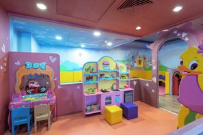 A children's playroom with a pink and blue color scheme, featuring a play kitchen, a toy car, and a large cartoon character. - Herods Palace Hotels & Spa Eilat (Eilat)