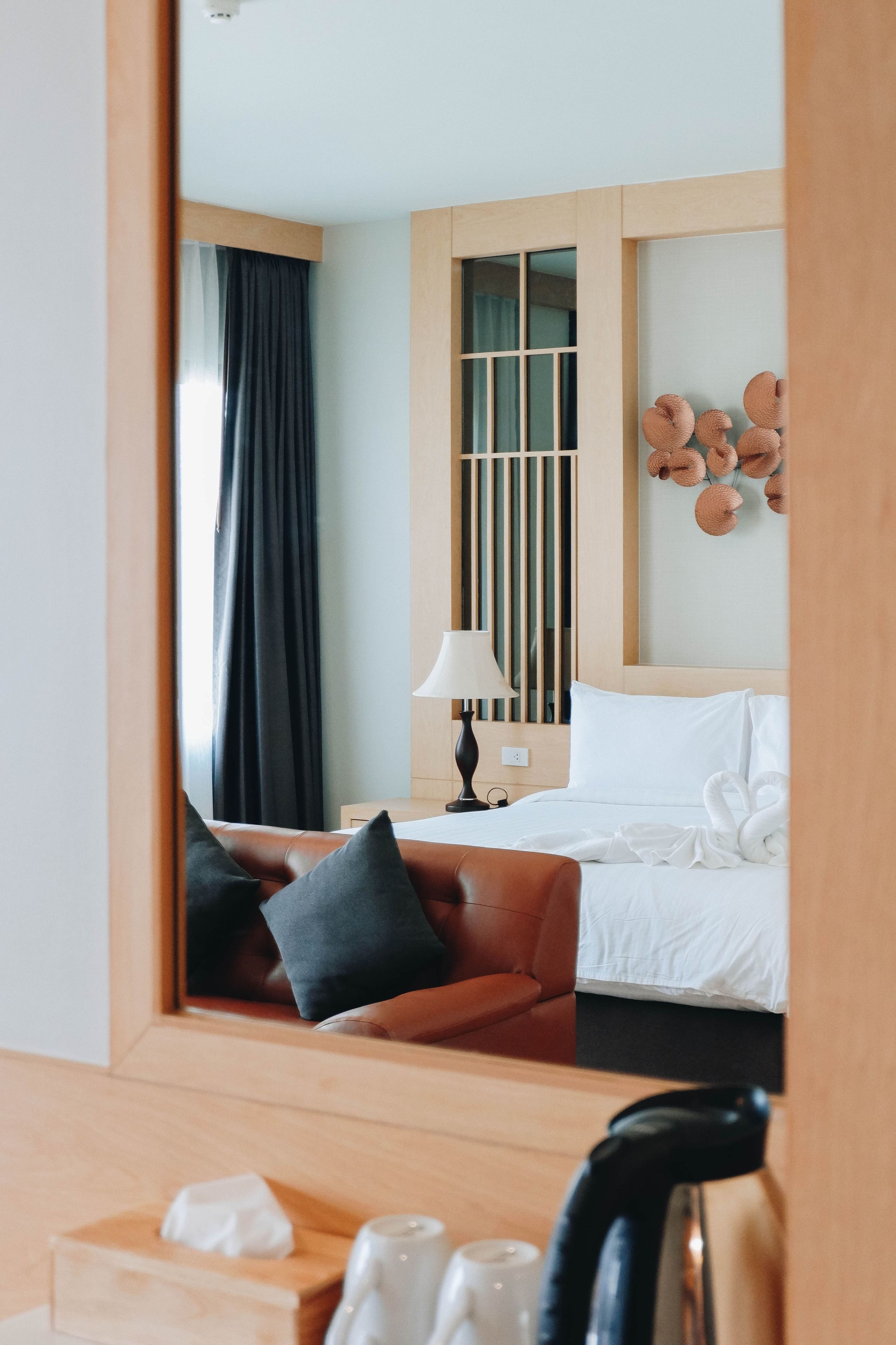 A hotel room with a bed, a desk, a chair, a lamp, and a decorative wall piece.