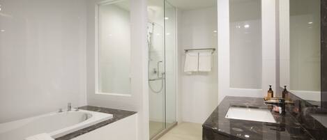 A modern bathroom with a bathtub, a glass-enclosed shower, a vanity with a sink, and a large mirror.