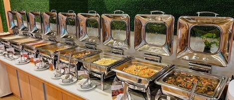 Ein Buffet mit mehreren Selbstbedienungsstationen, an denen verschiedene Gerichte angeboten werden.