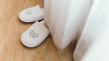 A pair of white slippers with a leaf design on a wooden floor.
