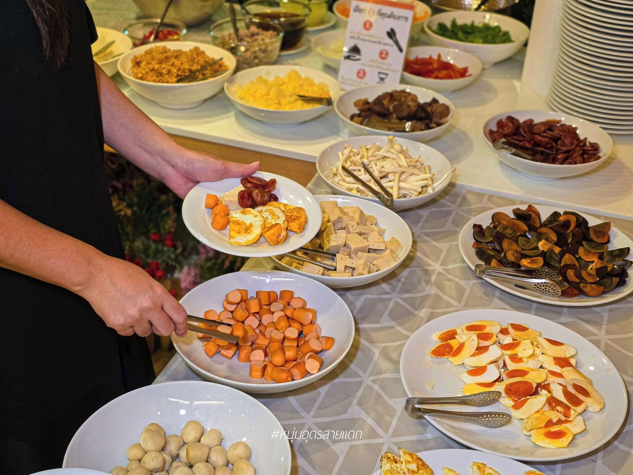 A buffet table with various dishes including tofu, carrots, mushrooms, and other prepared foods.