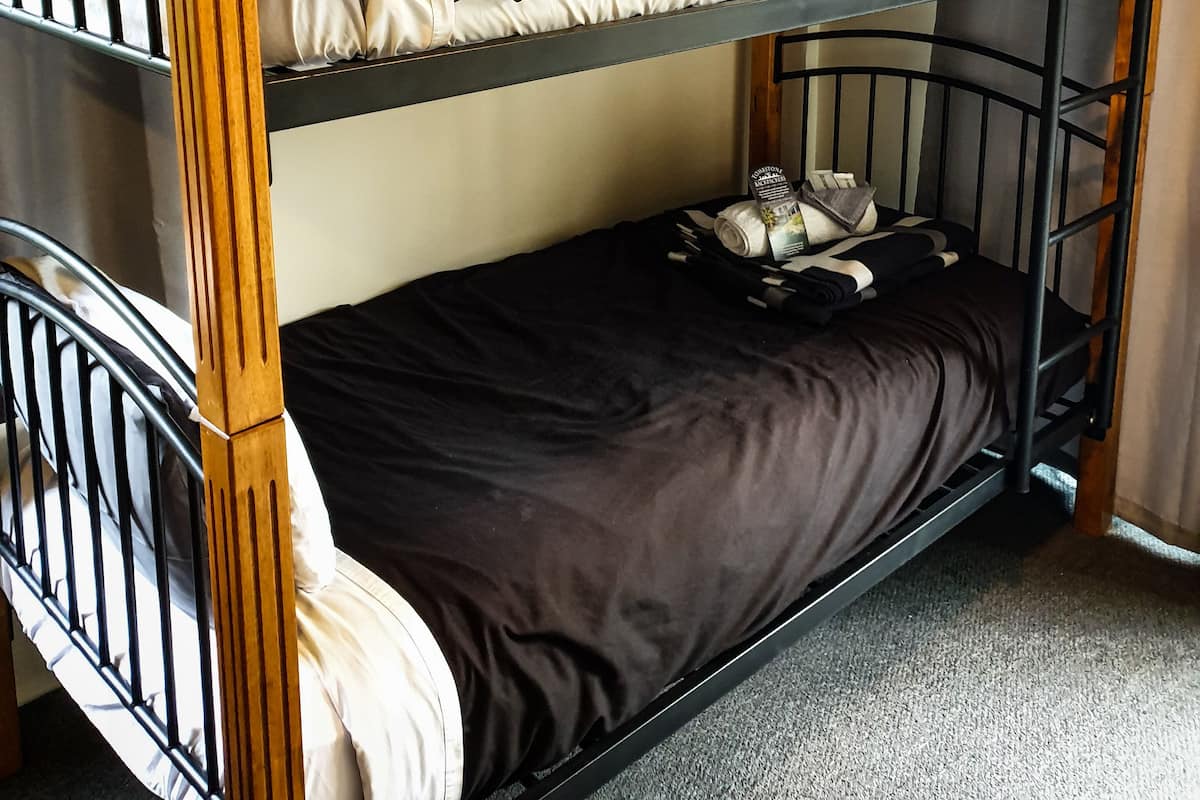 Una cama litera con dos niveles, cada uno con almohadas y mantas.