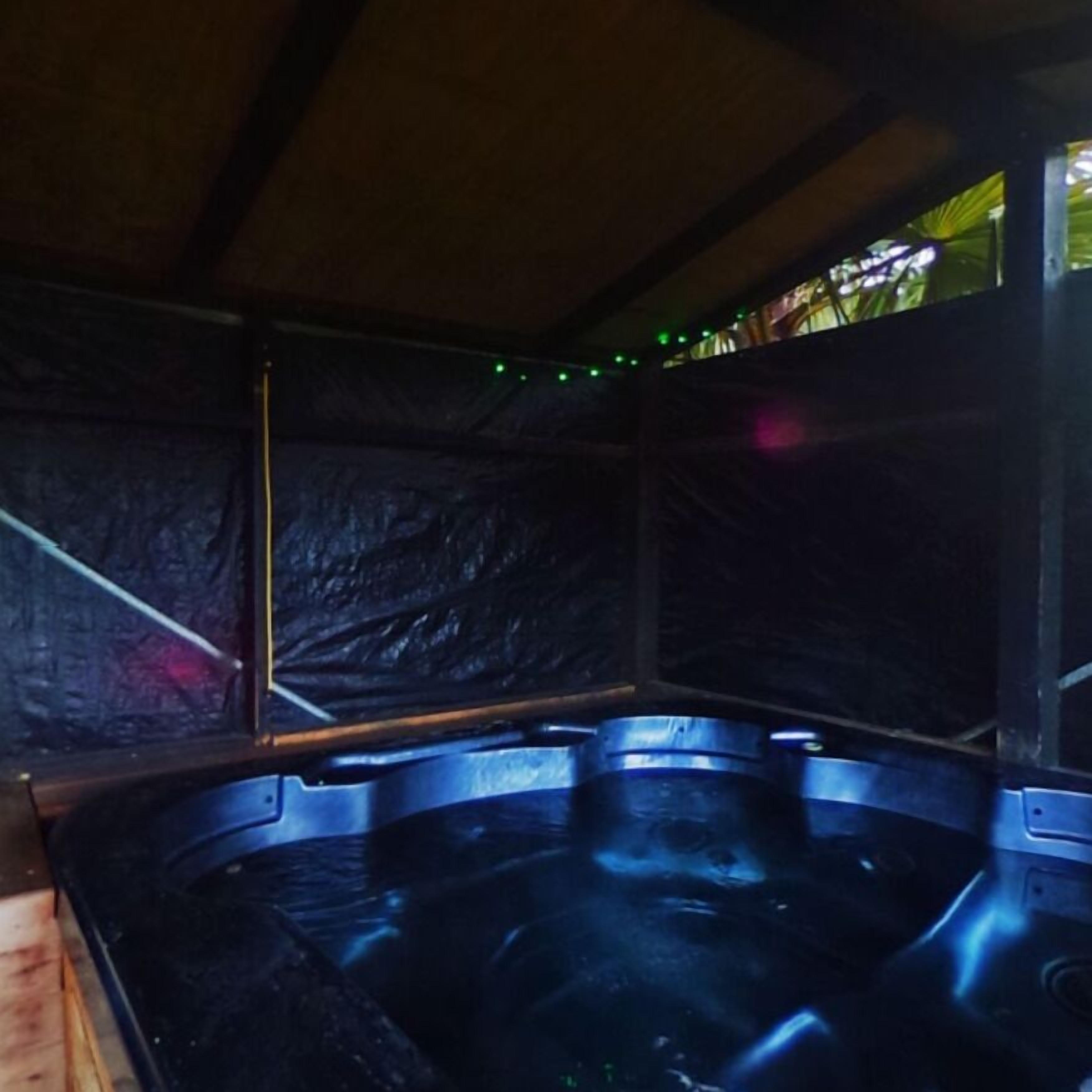 A hot tub area with a wooden floor and a ceiling with a wooden beam structure.