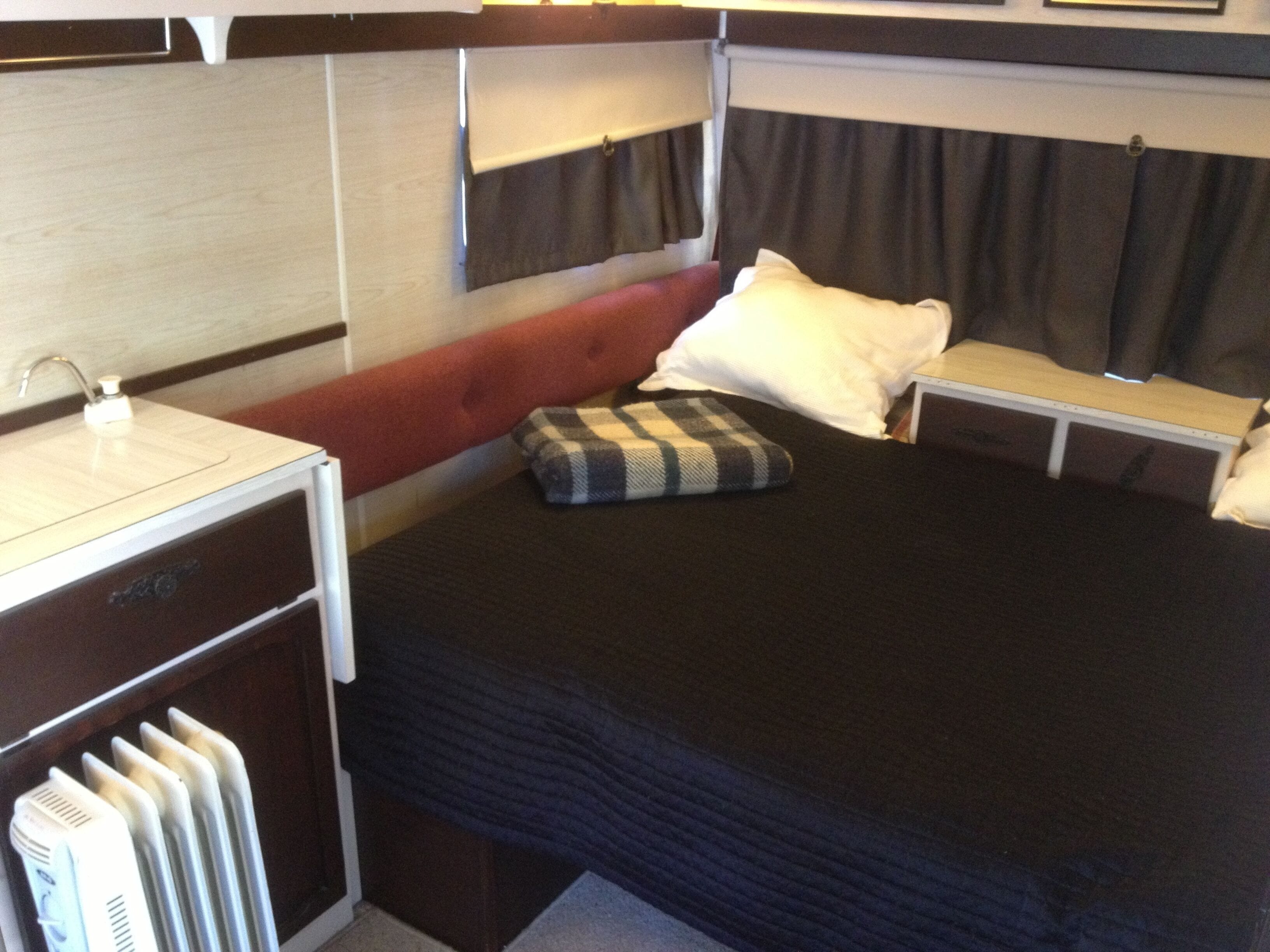 Un dormitorio compacto con cama individual, mesita de noche, escritorio pequeño y radiador.