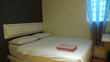 A single bed with a headboard, a bedside table, and a window with curtains.