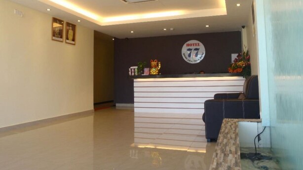 Zona de recepción de hotel con diseño moderno, que incluye un mostrador de recepción, un área de estar y un emblema en la pared.