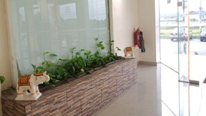 Zona de recepción con un separador de vidrio, mostrador de recepción, extintor y vista al exterior.