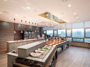 Una cocina moderna con una isla grande, encimeras de granito y vistas a la ciudad a través de amplios ventanales.