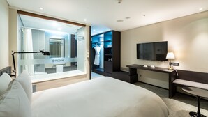Una habitación de hotel moderna con una cama grande, un escritorio, un televisor y un vestidor.