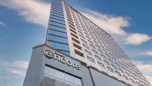 Un edificio alto de diseño moderno, con el logo 'Encore' destacado en la parte inferior.