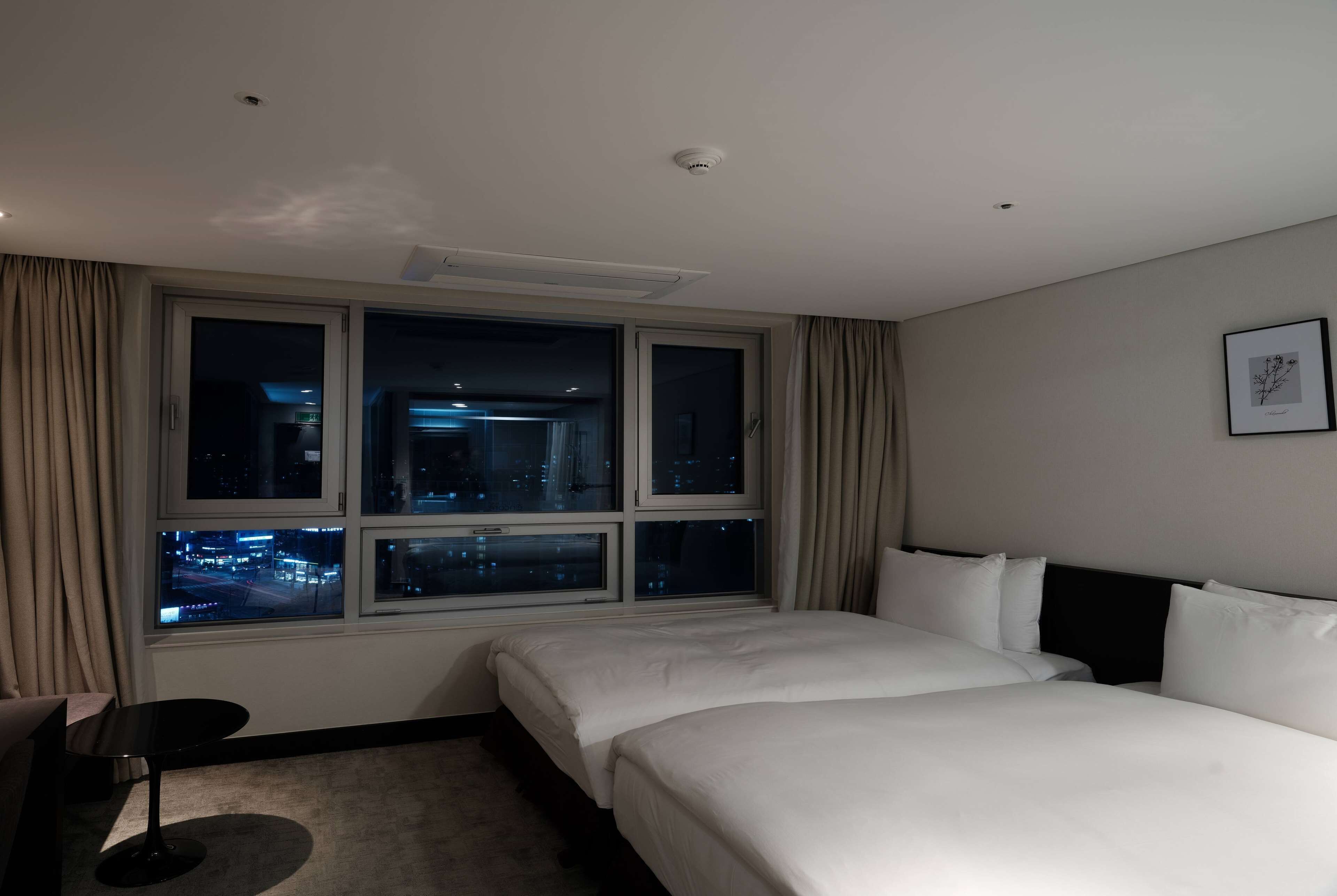 A hotel room with a large window, a bed, a desk, and a chair.