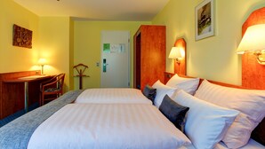 A hotel room with two beds, a desk with a chair, and two wall-mounted lamps. - Hotel Elbinsel (Hamburg)