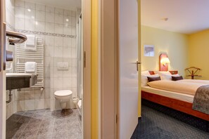 A hotel bathroom with a shower, toilet, and sink.