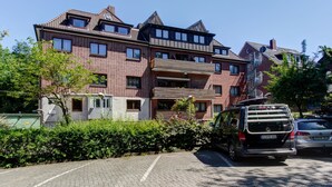 A multi-story residential building with a brick facade, multiple balconies, and a parking area with a van and a car. - Hotel Elbinsel (Hamburg)