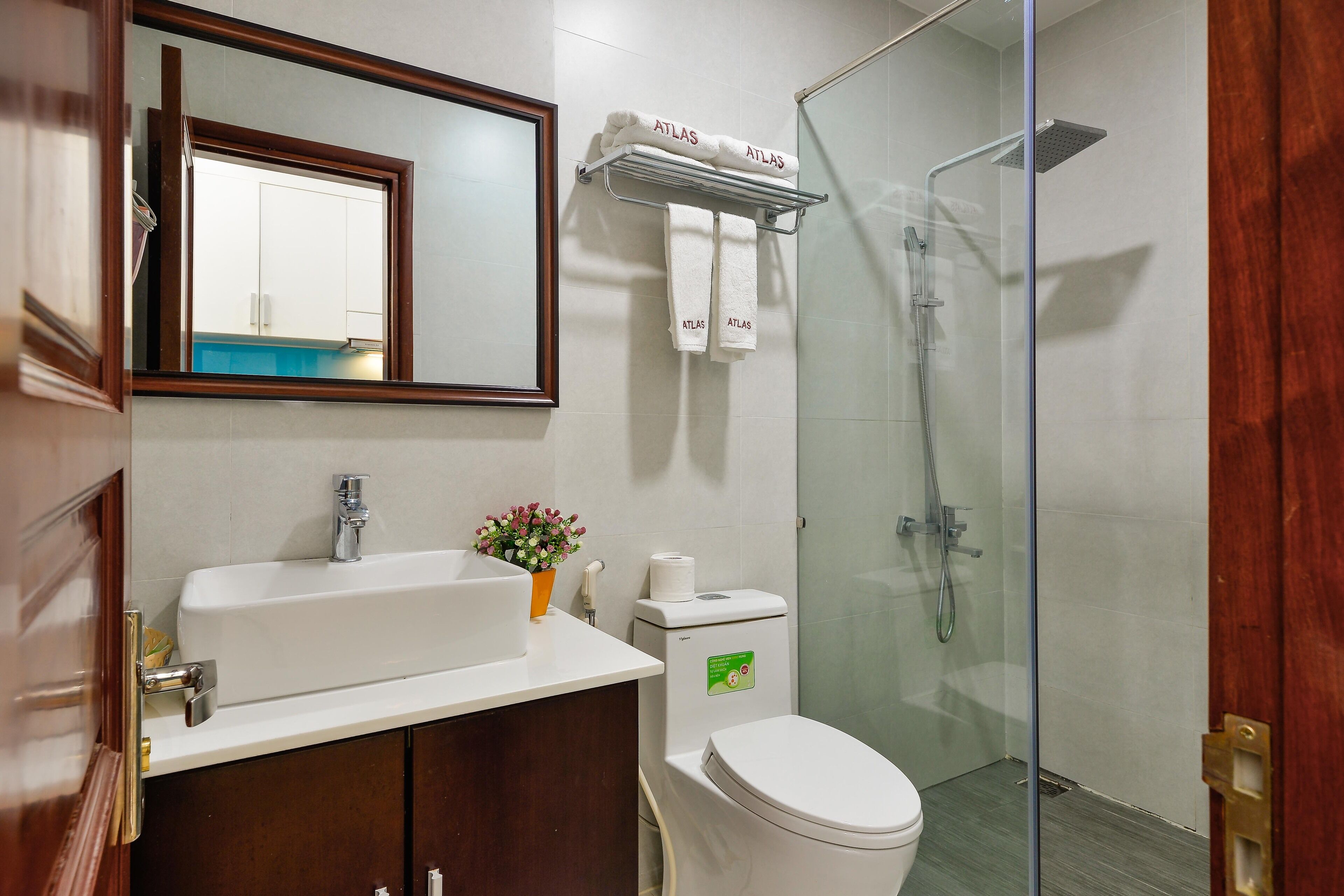 A bathroom with a white sink, a mirror, a shower, and a toilet.