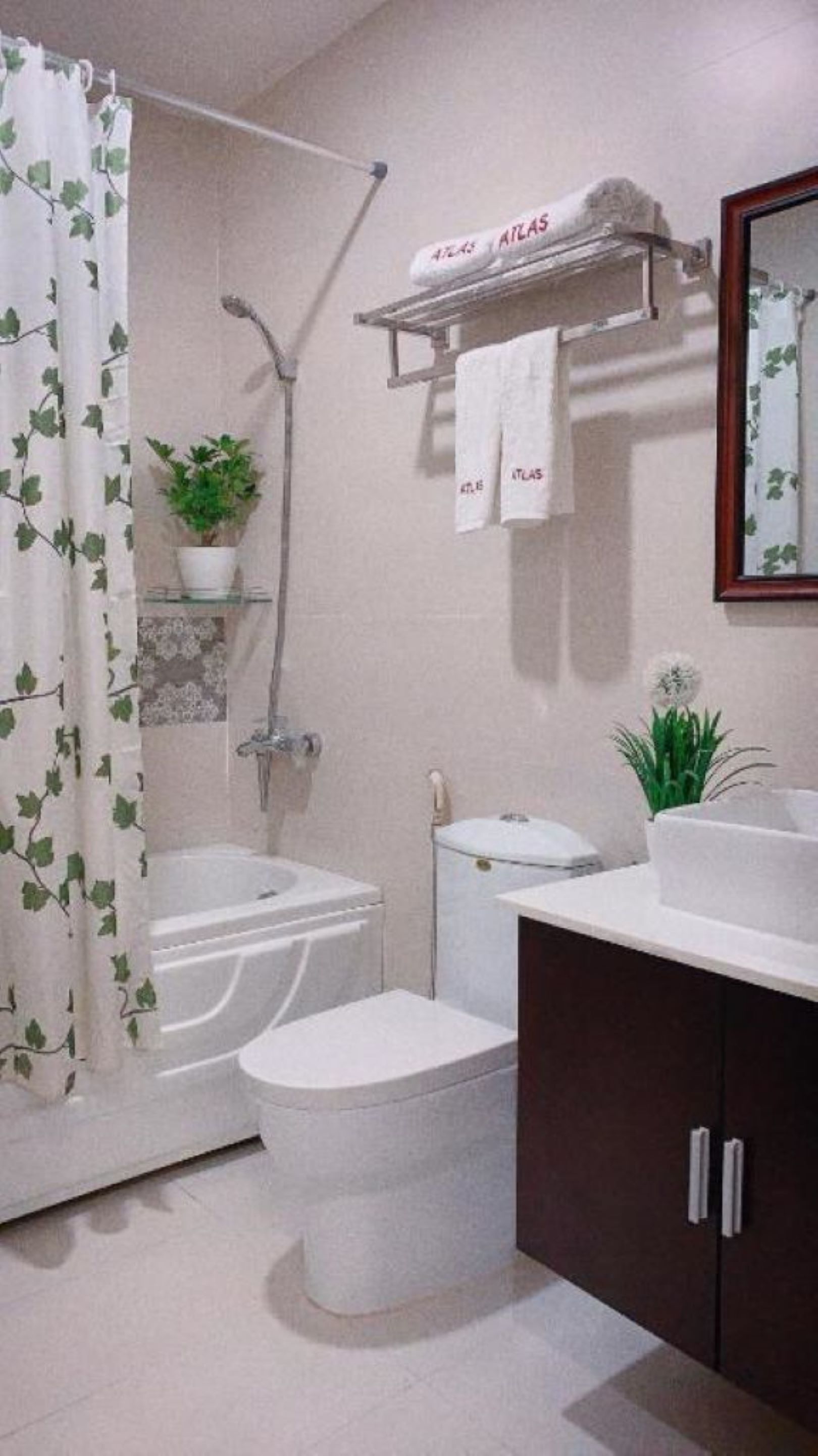 A bathroom with a shower, toilet, sink, and a mirror.