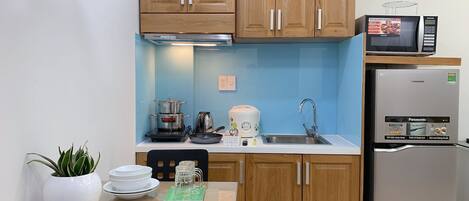A compact kitchen with wooden cabinets, a microwave, a refrigerator, and a small dining area with a table and chairs.
