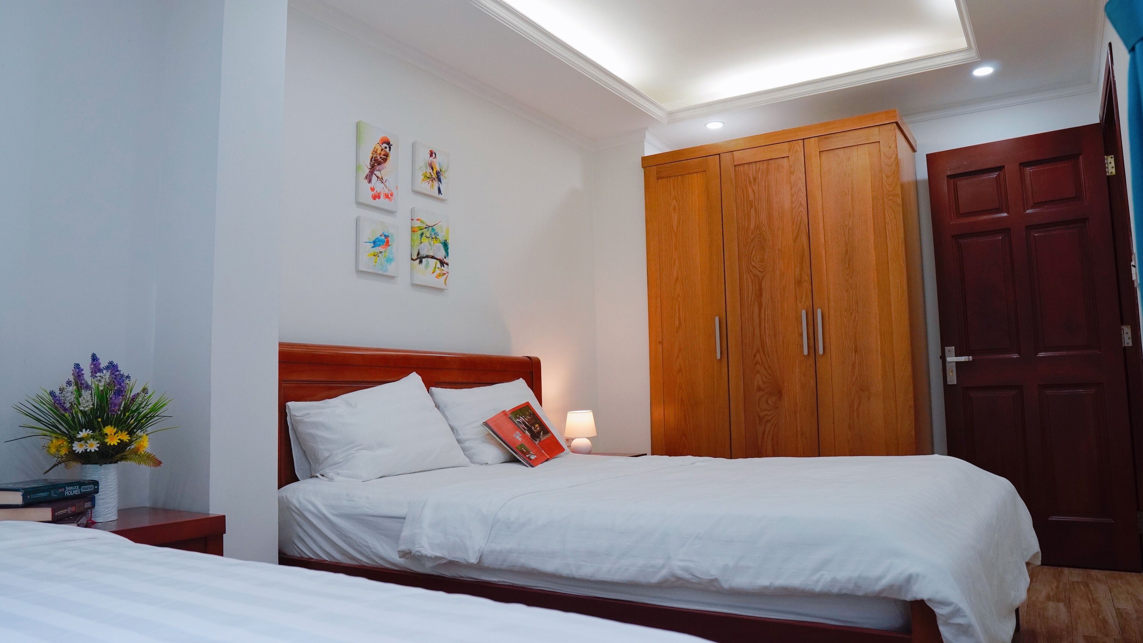 Quarto com cama de madeira, um guarda-roupa e uma mesa de cabeceira com abajur.