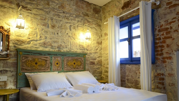 A bed with white linens and towels, a stone wall, and two wall-mounted lights. - Cunda Mavi Otel - Adults Only (Ayvalik)