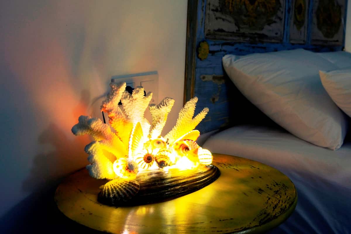 A bed with white pillows and a decorative lamp with a yellow base.