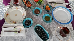 A table set with various dishes, including bread, vegetables, and condiments, on a marble table. - Cunda Mavi Otel - Adults Only (Ayvalik)