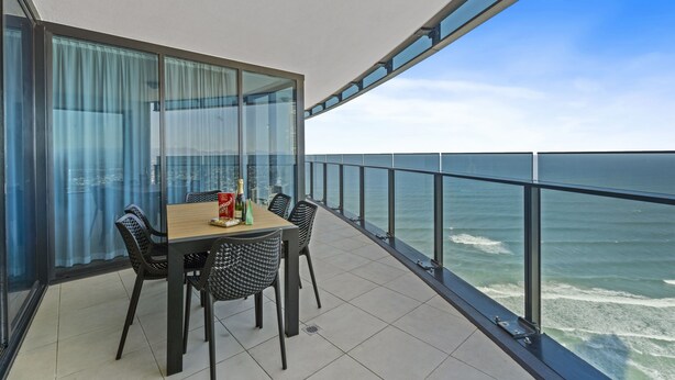 A balcony with a table and chairs, overlooking the ocean. - Esplanade (Soul) - Apartment Stay Private (Surfers Paradise)