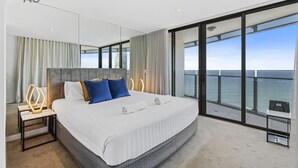 A modern hotel room with a large bed, a nightstand, a desk, and a view of the ocean. - Esplanade (Soul) - Apartment Stay Private (Surfers Paradise)
