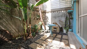 A courtyard with a stone pathway, potted plants, a wooden bench, and a small table. - Flowerinn (Magong)