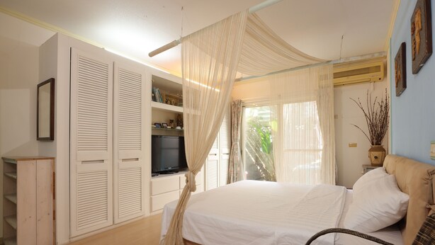 A bedroom with a bed, a television, a wardrobe, and a window with curtains. - Flowerinn (Magong)
