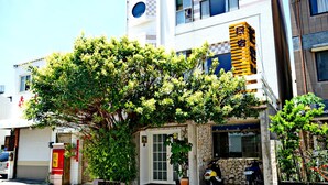 A building with a stone facade, a parked motorcycle, and a tree in front. - Flowerinn (Magong)