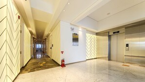 A hotel corridor with a fire extinguisher, an elevator, and a wall-mounted emergency exit sign. - HOTEL OSCAR (Daegu)