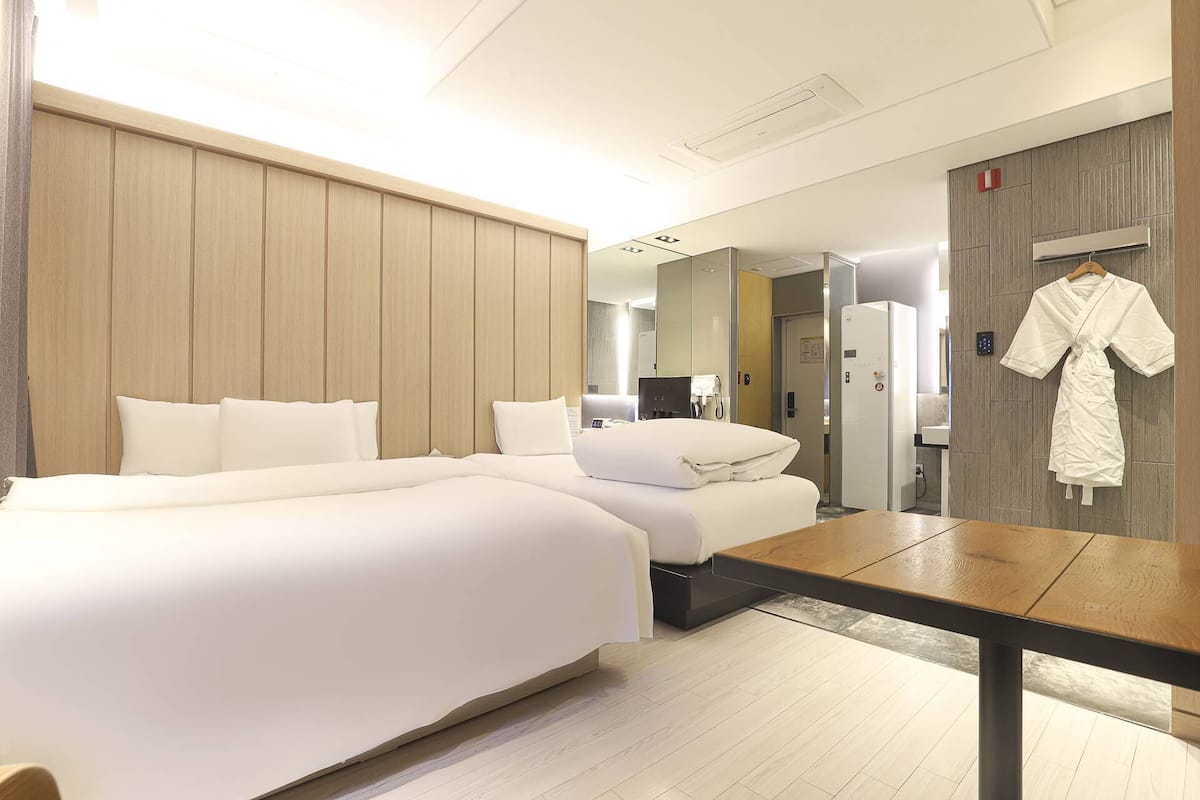 Ein Hotelzimmer mit einem großen Bett, einem Schreibtisch, einem an der Wand hängenden Bademantel und einer Dusche.
